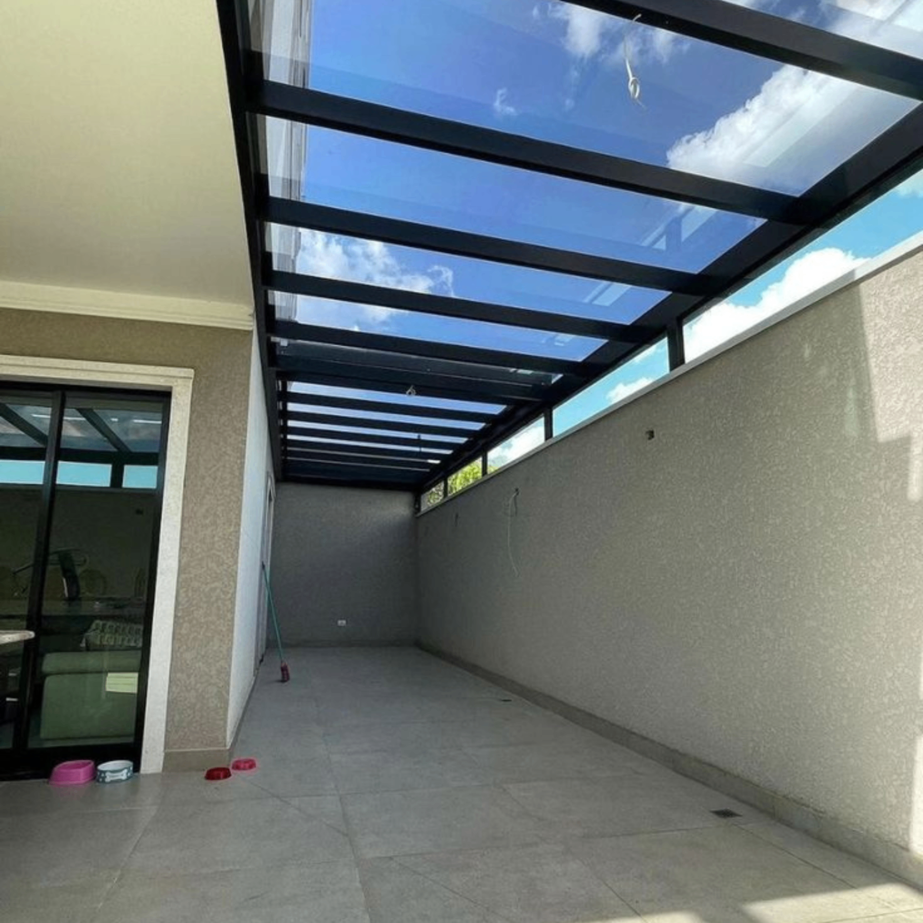 Cobertura em vidro com estrutura metálica preta em área lateral